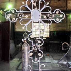 Кованый крест на кладбище с цветами 