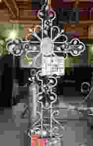 Кованый крест на кладбище с цветами 
